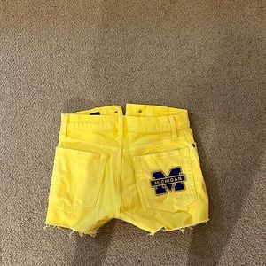 Yellow high waisted shorts with University of Michigan patch ironed on.
